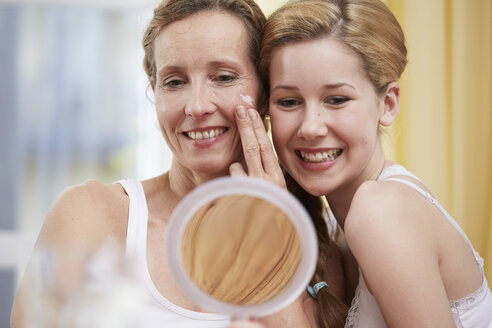 Portrait of mother and daughter heat to head with handheld mirror - STKF001060