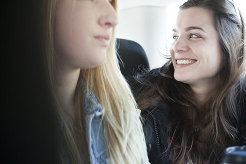 Zwei junge Frauen sitzen auf dem Rücksitz eines Autos - FEXF000088
