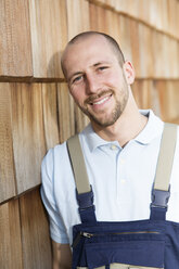 Confident craftsman leaning against at wooden wall - FKCF000006