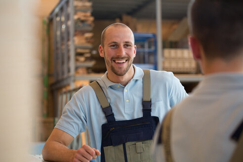 Smiling craftsman with colleague on shop floor - FKCF000048