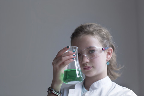 Weibliche Pupille hält Glas mit grünem Reagenz, lizenzfreies Stockfoto