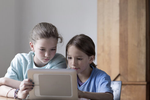 Bruder und Schwester schauen zu Hause auf einen Tablet-Computer - SGF000821