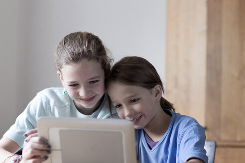 Bruder und Schwester schauen zu Hause auf einen Tablet-Computer - SGF000822