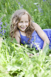 Portrait of smiling girl lying on flower meadow - MAEF008559