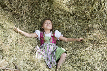 Germany, Bavaria, Girl in traditional dirndl lying in hay - MAEF008564
