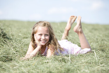Germany, Bavaria, Young girl lying on meadow with hay - MAEF008569