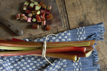 Sliced and whole rhubarb and kitchen towel on wood, elevated view - ASF005427
