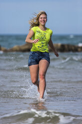 Weiblicher Teenager joggt am Ufer des Strandes - STSF000428