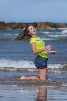 Weiblicher Teenager, der sich am Ufer des Strandes amüsiert - STSF000429