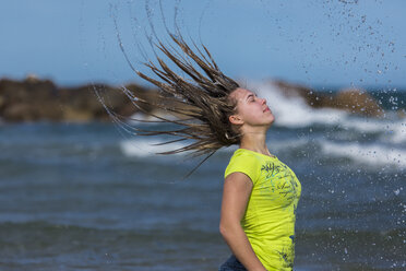 Weiblicher Teenager wirft ihr nasses Haar am Ufer des Strandes - STSF000430