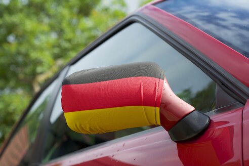 Deutschland, Nordrhein-Westfalen, Spiegelabdeckung mit deutscher Flagge auf rotem Auto - HAWF000362
