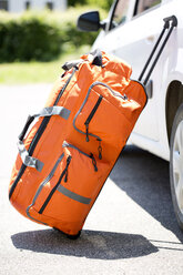 Germany, Bavaria, Rolling suitcase travelling bag leaning on a car - MAEF008587