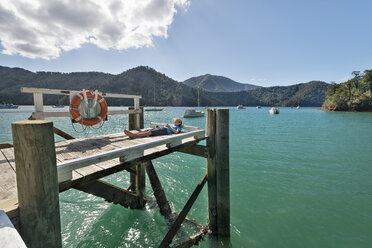New Zealand, South Island, Marlborough Sounds, Tennyson Inlet, boy lying on a wooden jetty - SHF001542