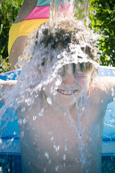 Mädchen bespritzt ihren Bruder im aufblasbaren Pool mit Wasser - SARF000706