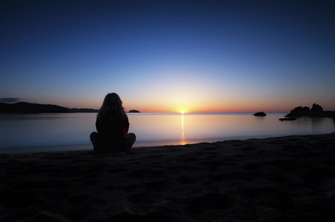 Spanien, Menorca, Frau beobachtet Sonnenuntergang an der Playa de Cavalleria, lizenzfreies Stockfoto