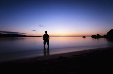 Spain, Menorca, Man watching sunset at Playa de Cavalleria - SMAF000215