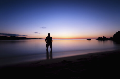 Spanien, Menorca, Mann beobachtet Sonnenuntergang an der Playa de Cavalleria - SMAF000215