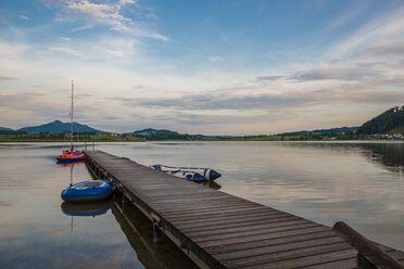 Germany, Bavaria, Fuessen, view to Hopfensee with jetty and rubber boats at twilight - WGF000358