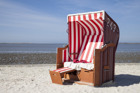 Deutschland, Niedersachsen, Dornum, Nessmersiel, rot-weißer Strandkorb mit Kapuze, lizenzfreies Stockfoto