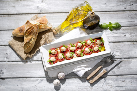 Mozzarellascheiben, Tomaten und Basilikumkraut auf weißem Teller, lizenzfreies Stockfoto