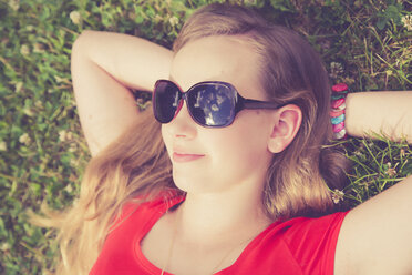 Germany, Bavaria, Female teenager with sunglasses lying on meadow - SARF000716