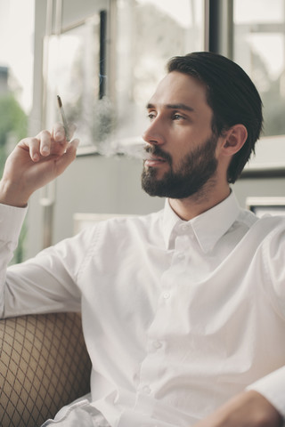 Porträt eines jungen Mannes, der Zigarillo raucht, lizenzfreies Stockfoto