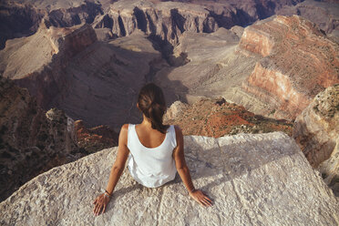 USA, Arizona, Frau sitzt an der Klippe des Grand Canyon, Rückansicht - MBEF001093