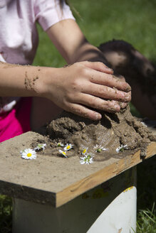 Hände eines kleinen Mädchens spielen mit Sand im Garten - YFF000197