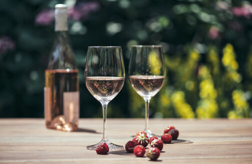 Zwei Gläser Roséwein, Weinflasche, Erdbeeren und Himbeeren auf Holztisch - IPF000149