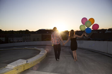 Teenage couple with balloons on parking ramp - FKF000568