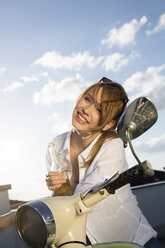 Glückliches Teenager-Mädchen mit Flasche am Moped - FKF000592