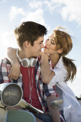 Glückliches jugendliches Paar im Freien auf einem Motorroller - FKF000600