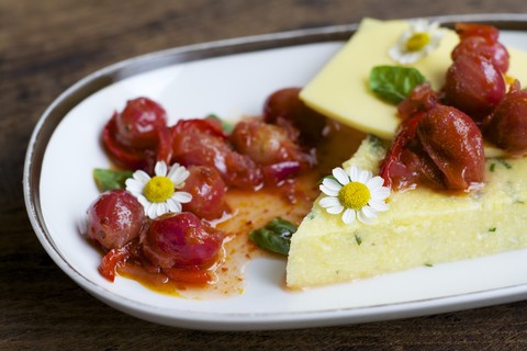 Platte mit Kräuterpolenta, veganem Käse, Stachelbeeren und Chili-Relish, lizenzfreies Stockfoto