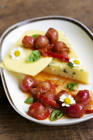 Platte mit Kräuterpolenta, veganem Käse, Stachelbeeren und Chili-Relish, lizenzfreies Stockfoto