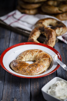 Teller mit selbstgebackenem Bagel und Schüssel mit Frischkäse - SBDF000968