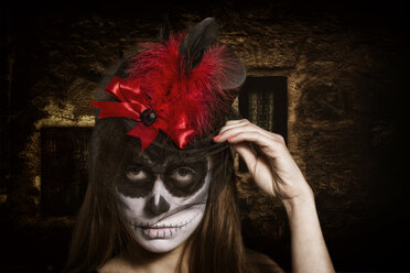 Porträt einer Frau mit Totenkopf-Make-up, die einen Zylinder mit roter Feder trägt, Studio-Aufnahme - STB000189