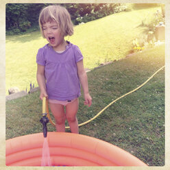 Germany, Rhineland-Palatinate, Kaiserslautern, little girl with hose and paddling pool - LVF001543