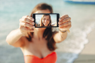 Indonesia, Gili Islands, woman on the beach showing smartphone with her selfie - EBSF000245