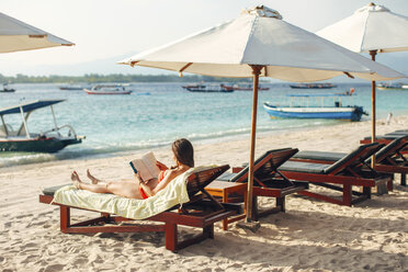Indonesia, Gili Islands, woman lying on a beach chair reading a book - EBSF000247