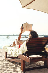 Indonesia, Gili Islands, woman lying on a beach chair reading a book - EBSF000248