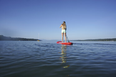 Deutschland, Bayern, junge Frau stehend auf Stand Up Paddle Board am Starnberger See, Rückansicht - FAF000019