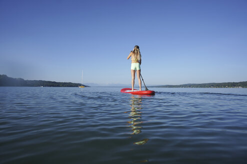 Germany, Bavaria, young woman standing on stand up paddle board at Lake Starnberg, back view - FAF000019