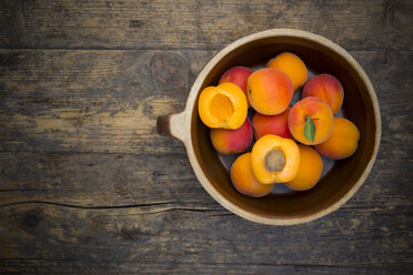 Bowl of sliced and whole apricots on wood, elevated view - LVF001533