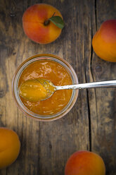Glass of apricots jam and apricots on wood, elevated view - LVF001536