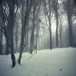 Germany, man standing in snow-covered forest - DWI000120