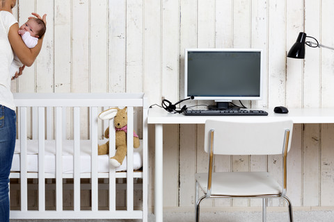 Frau im Home Office mit ihrem Baby, lizenzfreies Stockfoto