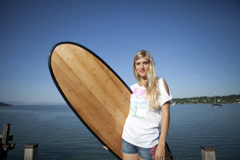 Portrait of young woman with surfboard in front of a lake - FAF000024