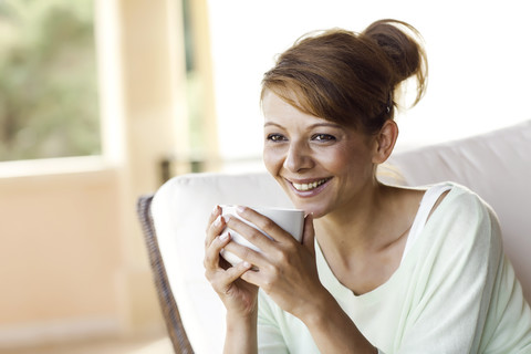 Lächelnde brünette Frau hält Tasse, lizenzfreies Stockfoto