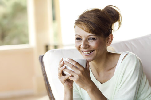 Lächelnde brünette Frau hält Tasse - GDF000346