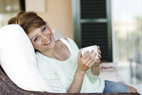 Smiling brunette woman holding cup - GDF000350